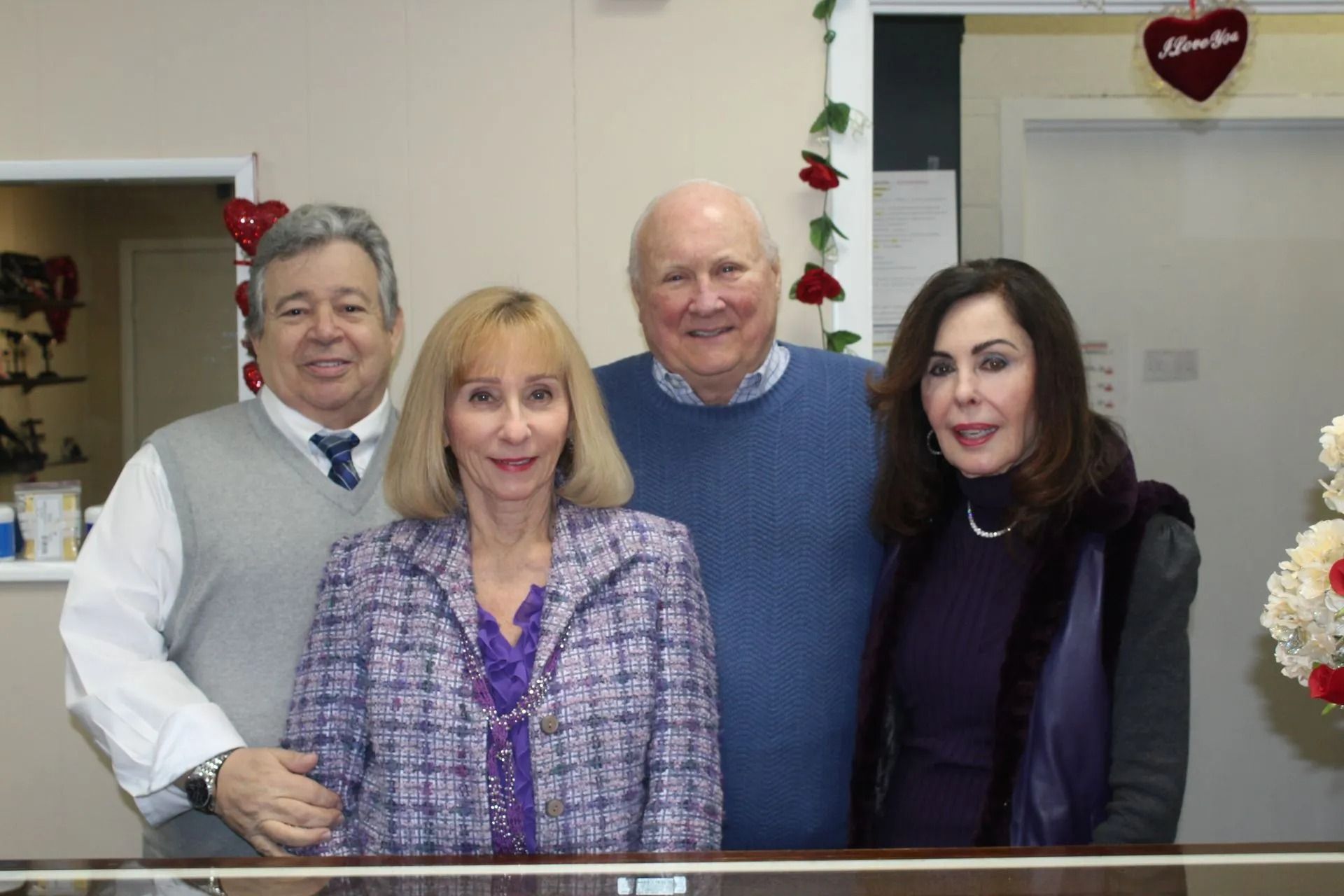 Four people standing indoors, smiling at the camera in a decorated office or lobby.