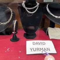 David Yurman jewelry display on black busts and stands over a red cloth.