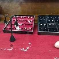 Red velvet jewelry display trays with earrings on a table, with a black stand in front.