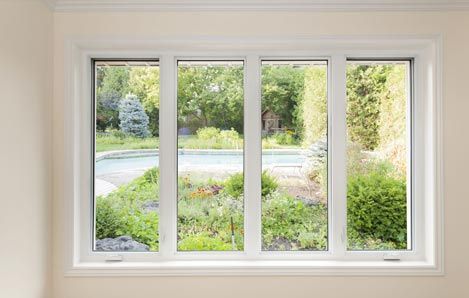 A large white window with a view of a garden and a pool.