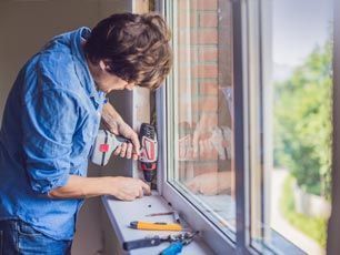A man is installing a window with a drill.