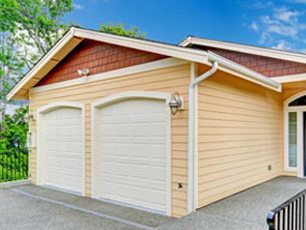 A yellow garage with two white garage doors and a red roof.