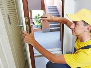 A man in a yellow hat is fixing a door with a screwdriver.