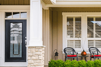 A house with a black door and a porch with chairs and a table.