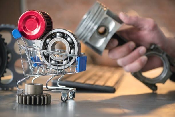 Small shopping cart filled with engine parts, hand holding a piston, keyboard in background.