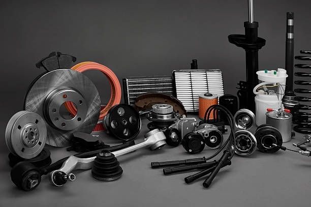 Car parts assortment on a gray background, including brakes, shocks, filters, and springs.