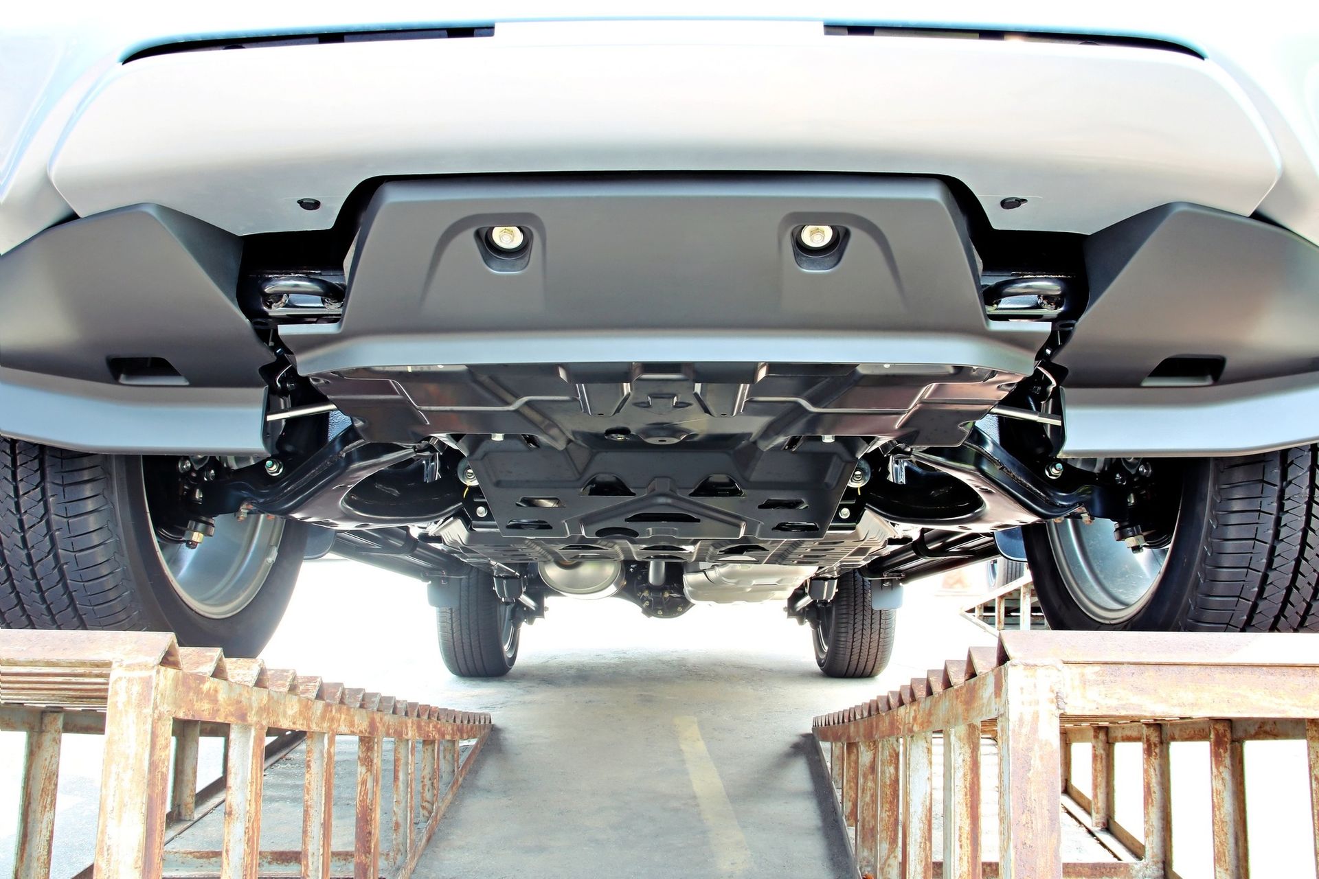 Undercarriage of a gray vehicle on ramps, showcasing the underbody and suspension.