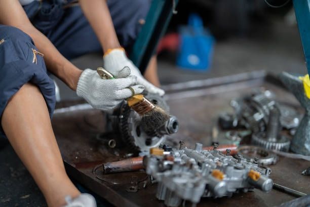 Mechanic in gloves using pliers on car engine components in a workshop.