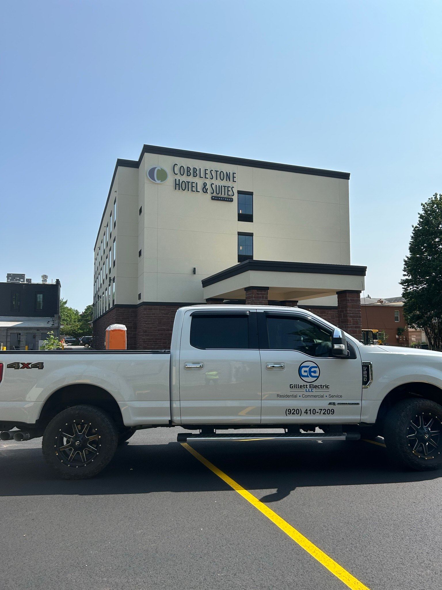 A white truck is parked in front of a large building