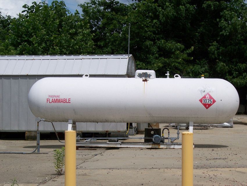 A large white propane tank with a red sign that says flammable