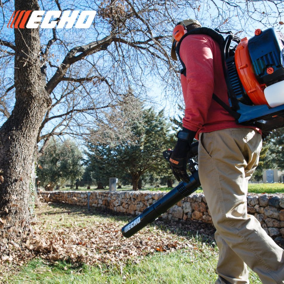 A man is using an echo leaf blower to blow leaves