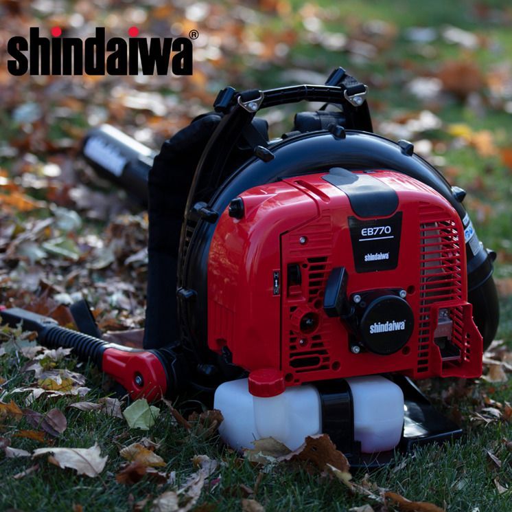 A red shindaiwa leaf blower is sitting in the grass