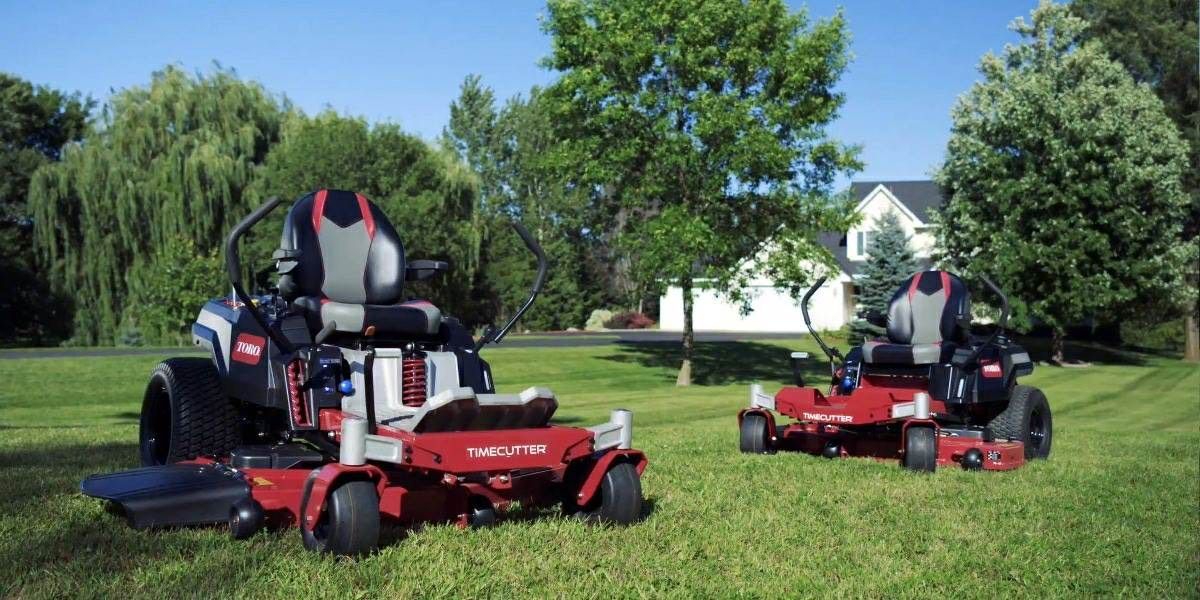 Two lawn mowers are sitting on top of a lush green lawn.