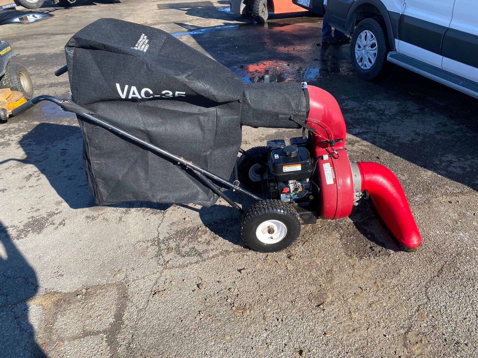 A vacuum cleaner is sitting on the ground next to a car.