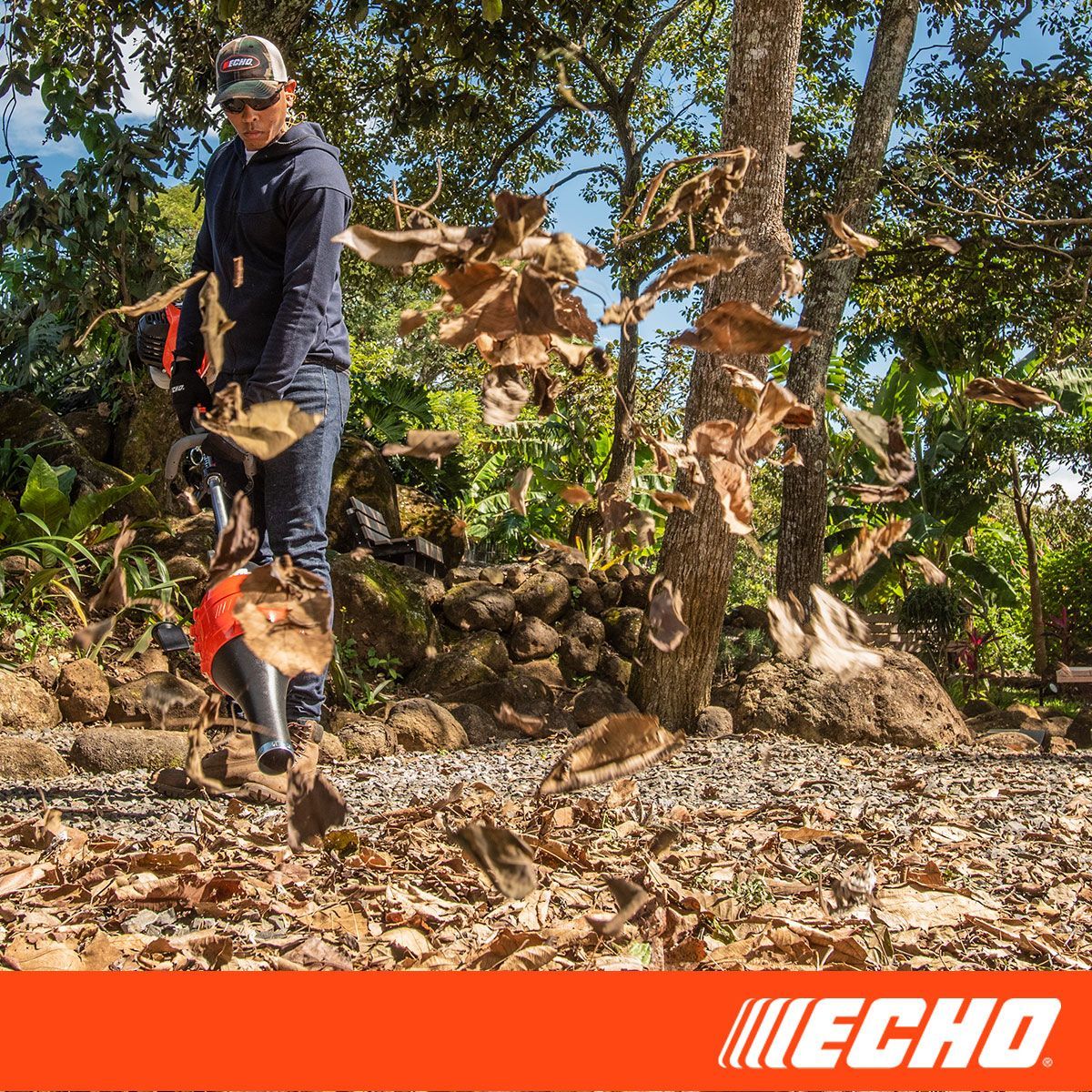 A man is blowing leaves with a echo blower.