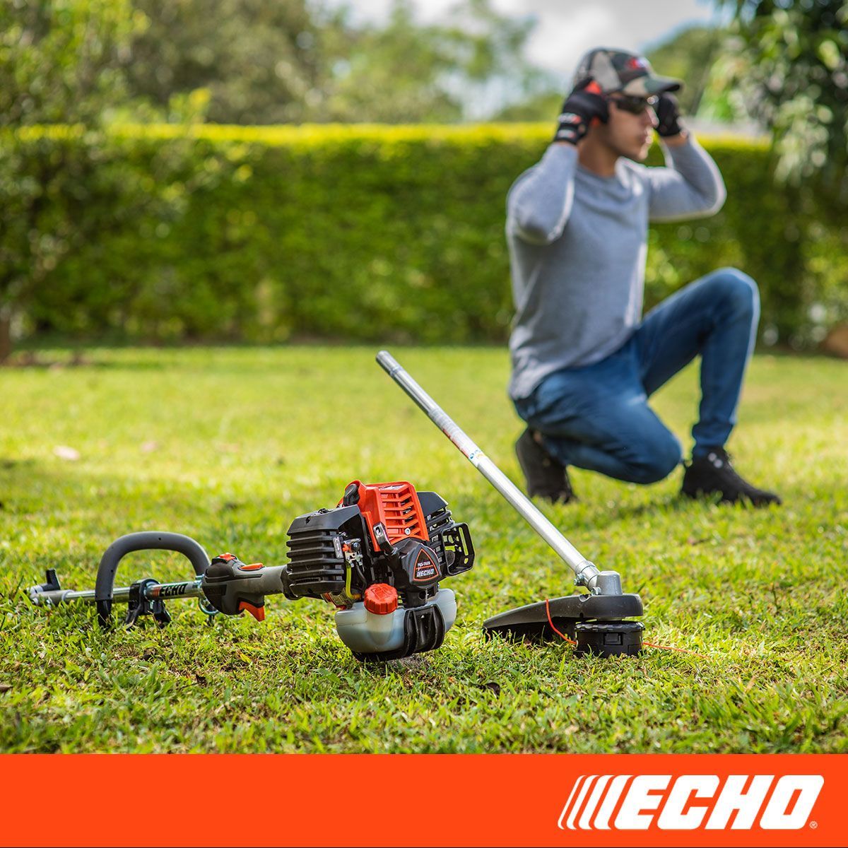 A man is kneeling down next to a echo lawn mower