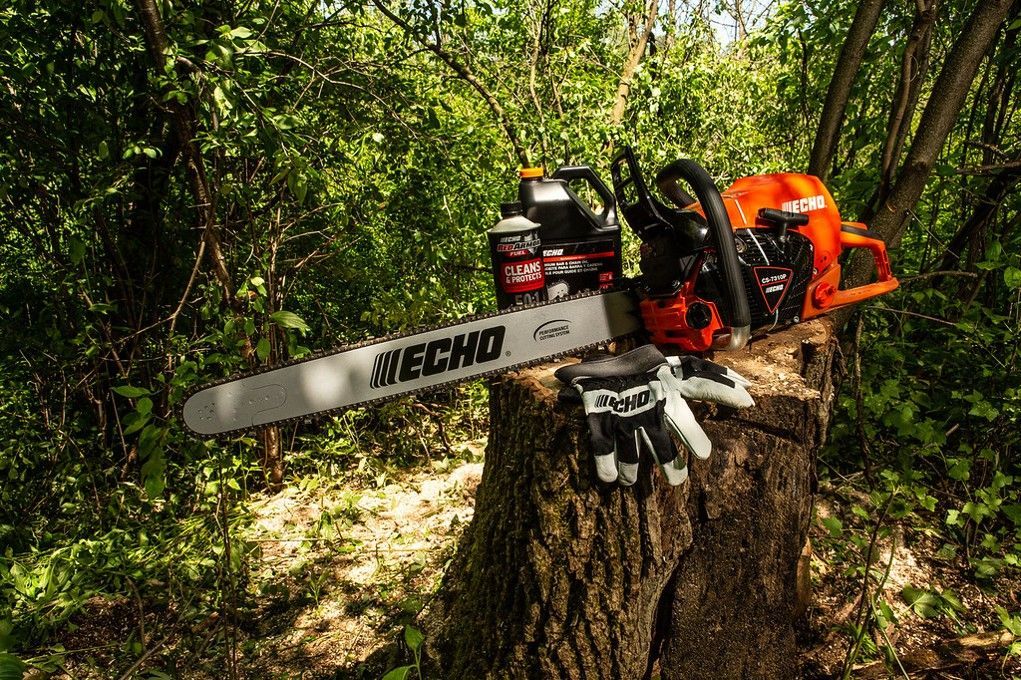 A chainsaw is sitting on top of a tree stump in the woods.