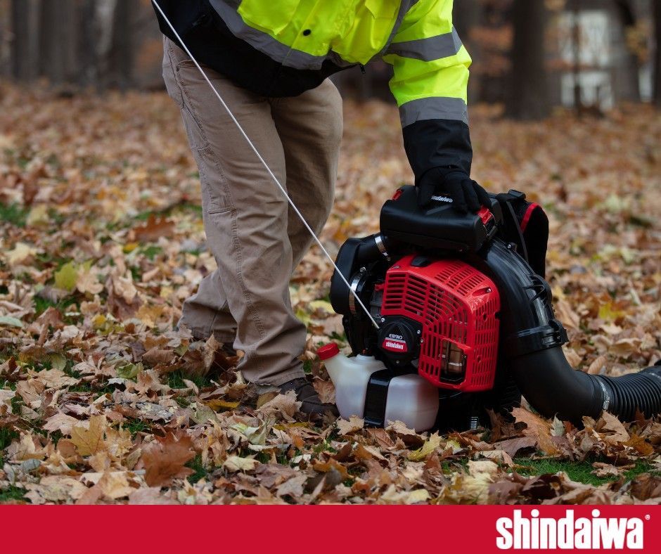 A man is using a shindaiwa leaf blower to blow leaves