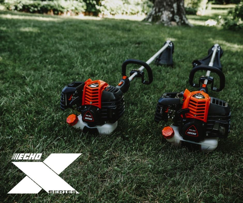 Two echo trimmers are sitting on top of a lush green field.