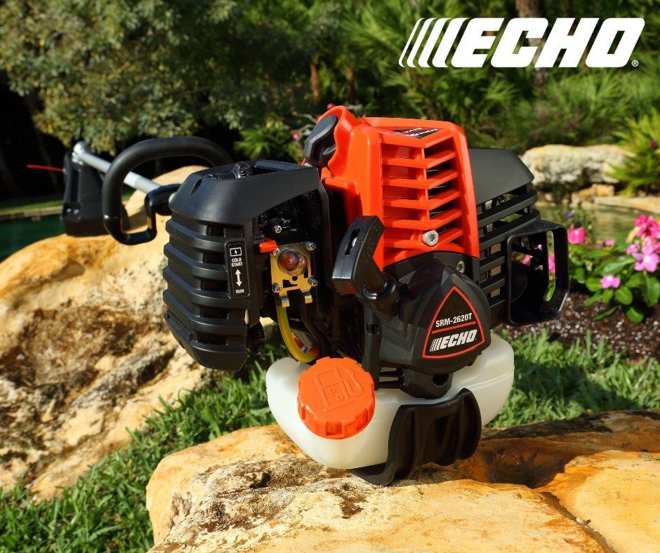 An echo trimmer is sitting on a rock in the grass