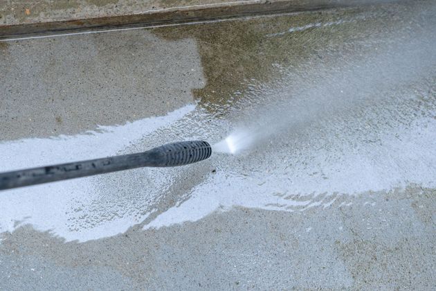 Pressure washer cleaning a concrete surface; water spray visible.