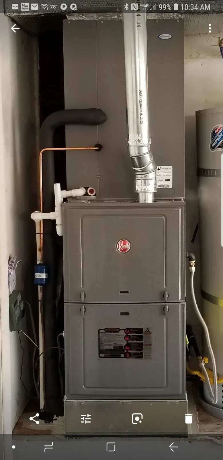 A Rheem HVAC system installed in an enclosed space with a water heater visible on the right.