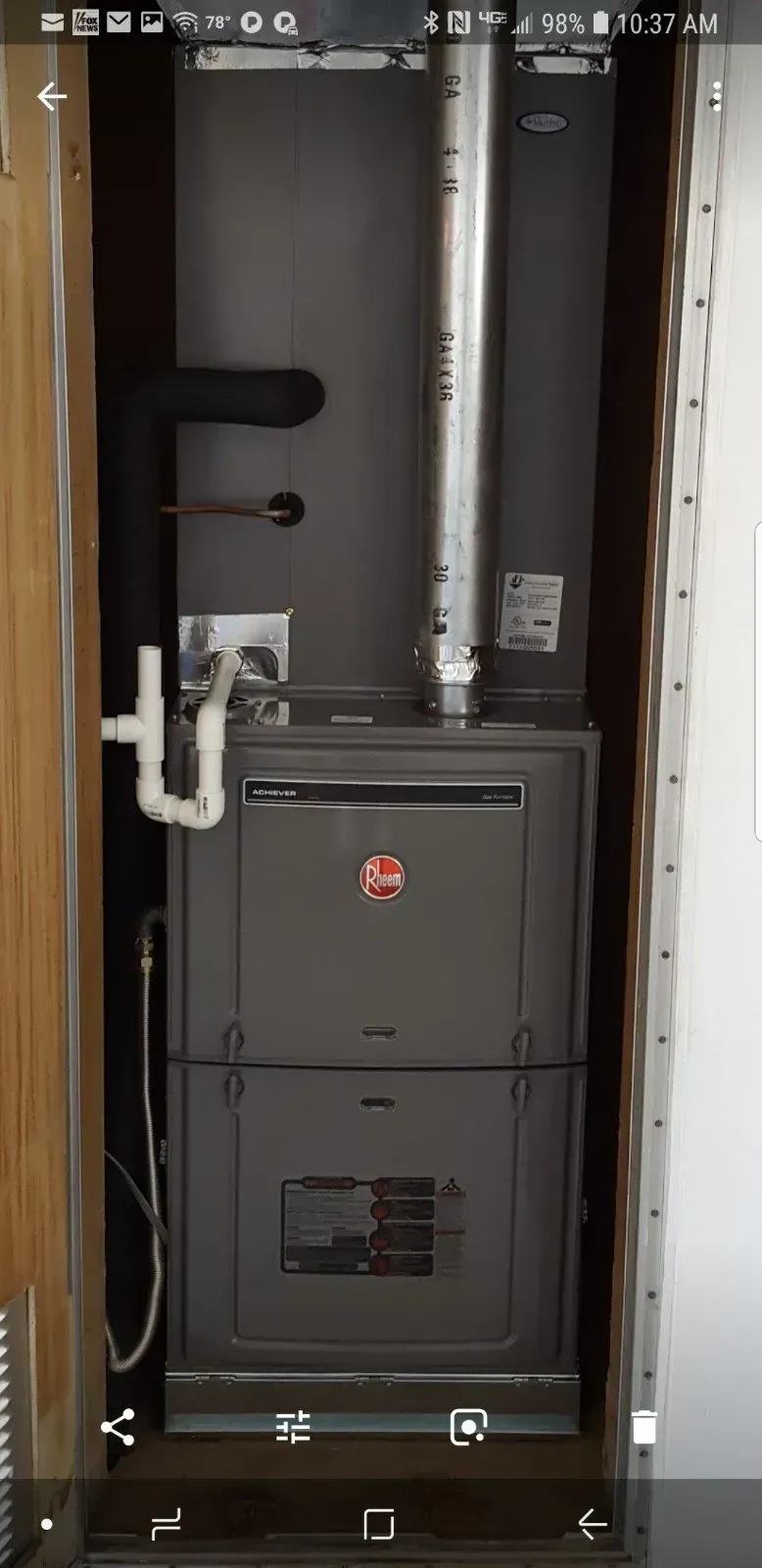 A Rheem furnace installed in a utility closet with vent pipes visible.