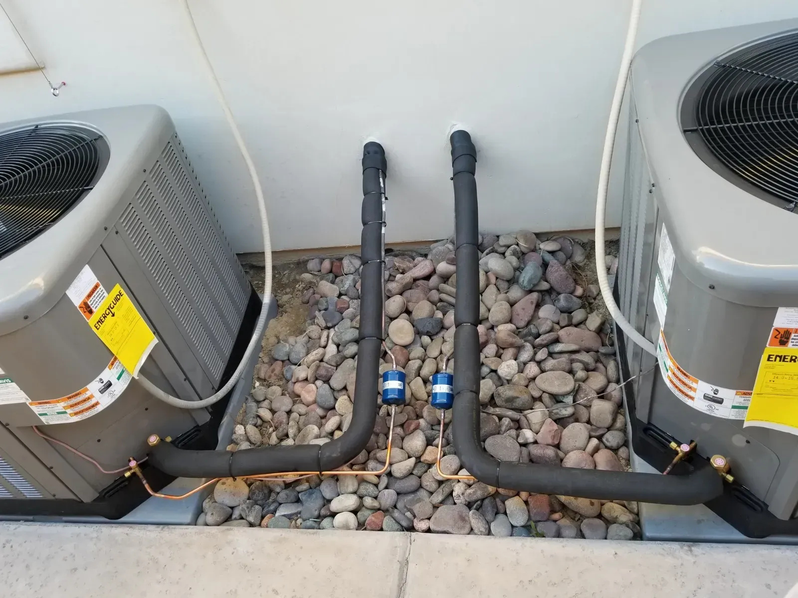 Two outdoor air conditioning units with insulated copper refrigerant lines.