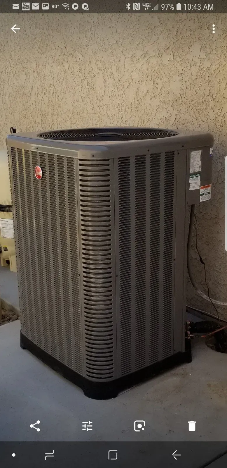 An air conditioning unit in a residential setting. Gray and black.