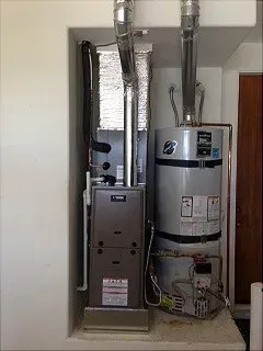 Furnace and water heater in a recessed alcove, with silver ductwork.