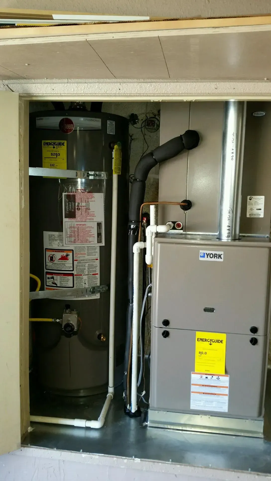 Water heater and furnace in a utility closet with vent and pipes.