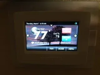 A touchscreen thermostat displays a room temperature of 77 degrees, cooling to 78, and has options for fan, mode, and menu.