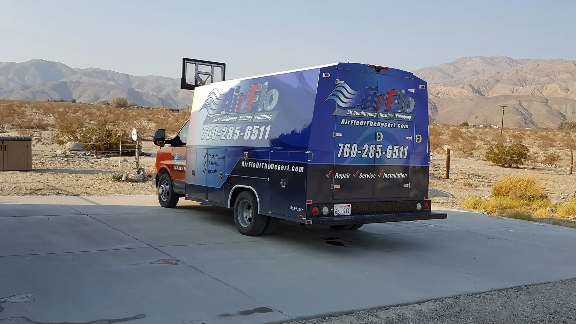 Delivery truck with colorful graphics, parked on concrete in a desert landscape.