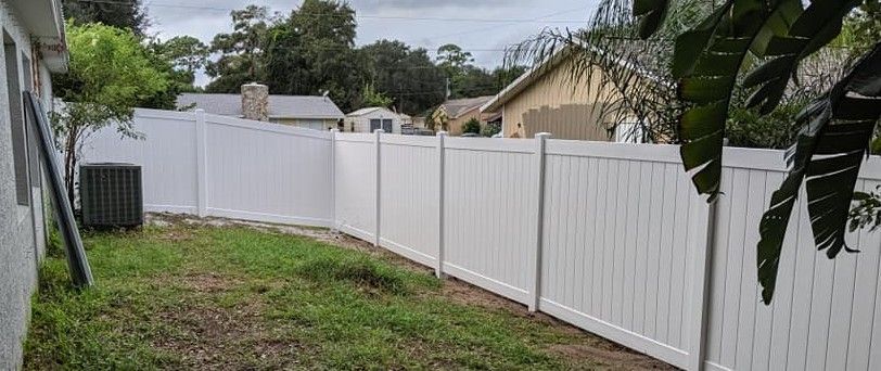 There is a white fence in the backyard of a house.