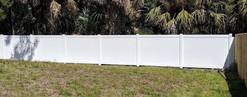 A white fence is sitting in the middle of a grassy field.
