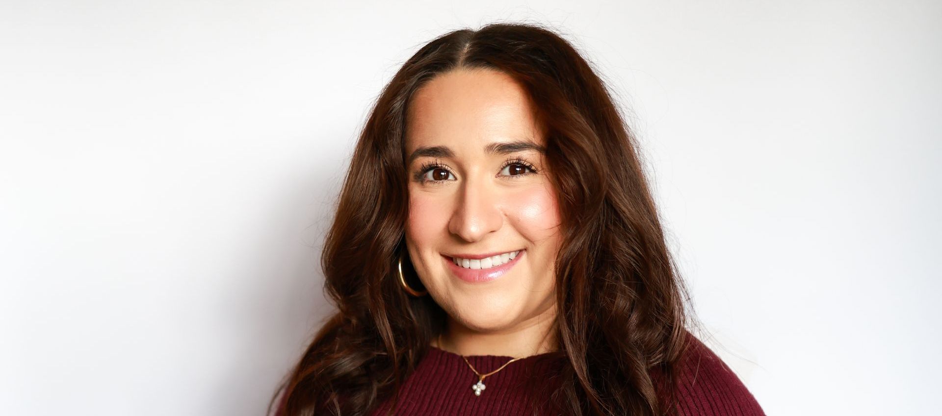 A woman with long brown hair is smiling for the camera.