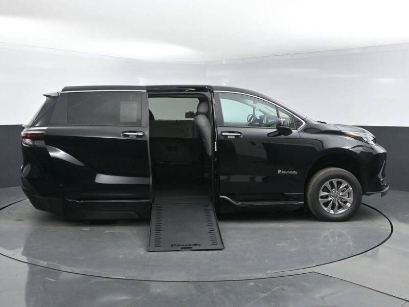 Black wheelchair-accessible van with ramp deployed. Side view, indoors.