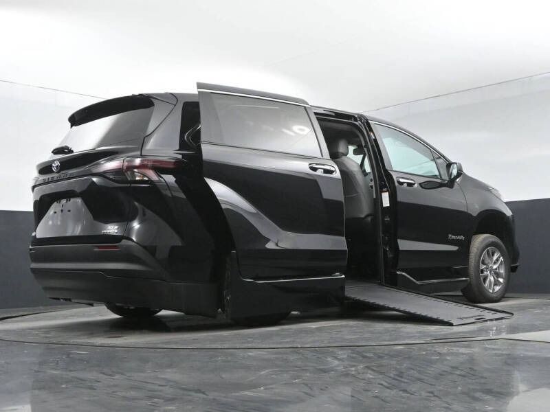 Black wheelchair-accessible van with open side door and ramp extended.