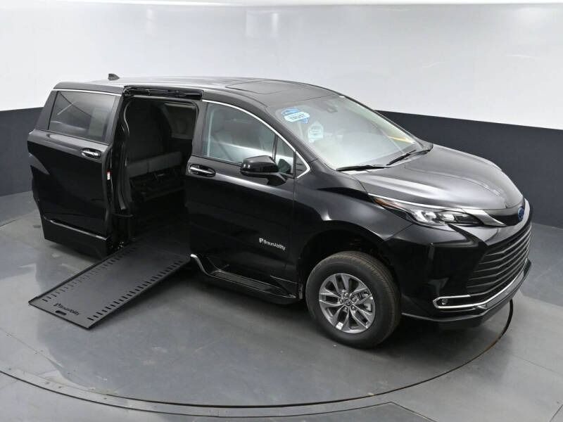 Black wheelchair-accessible Toyota Sienna van with ramp deployed, parked indoors.