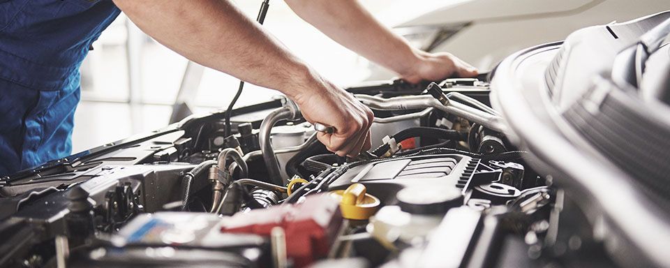 A man is working on the engine of a car.