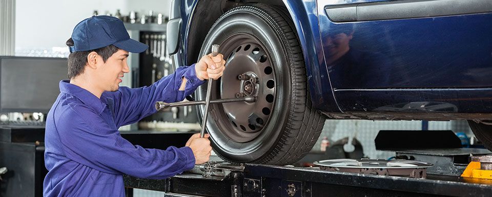 A man is working on a car wheel in a garage.
