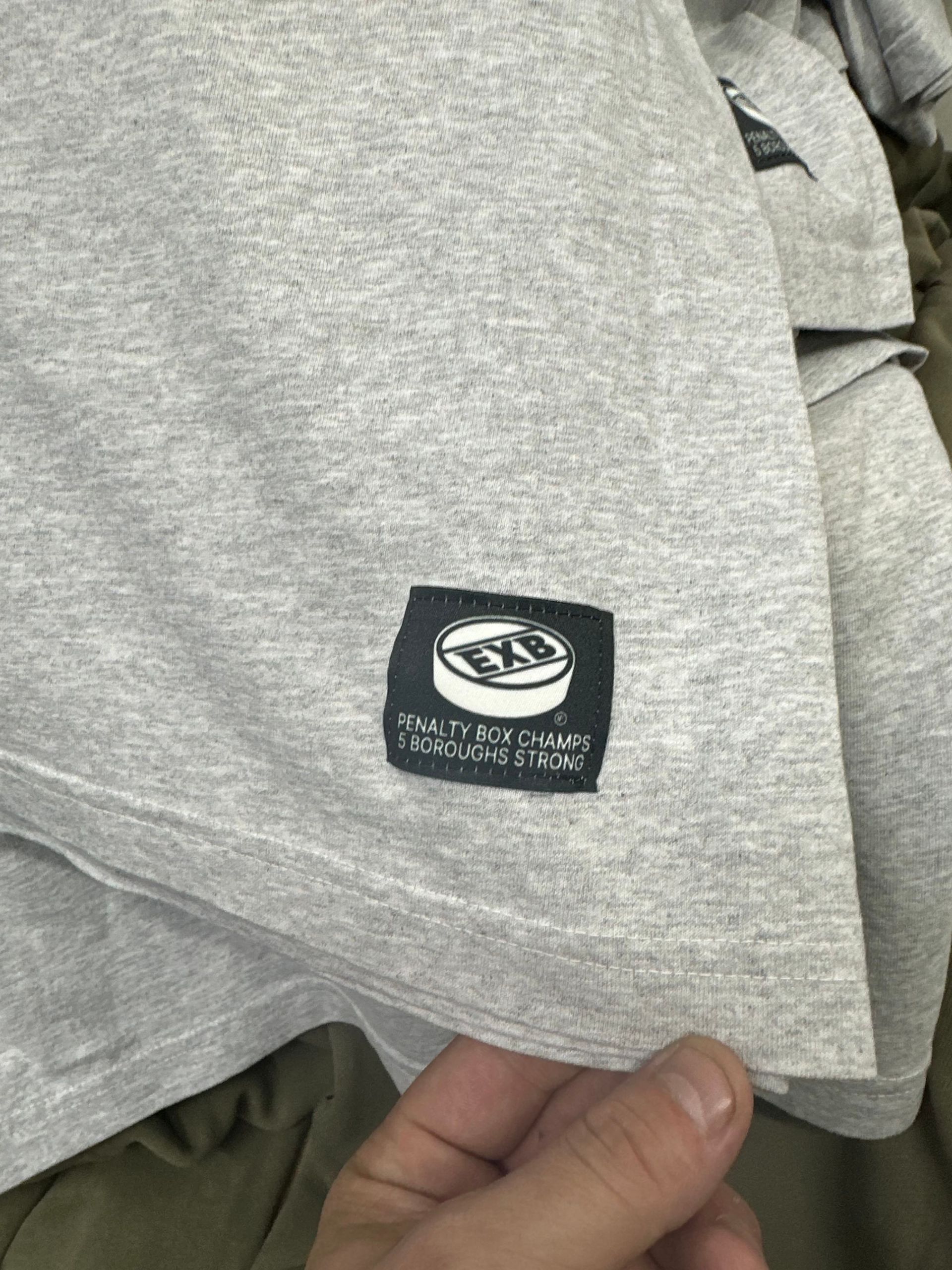 a person is holding a grey shirt with a label on it