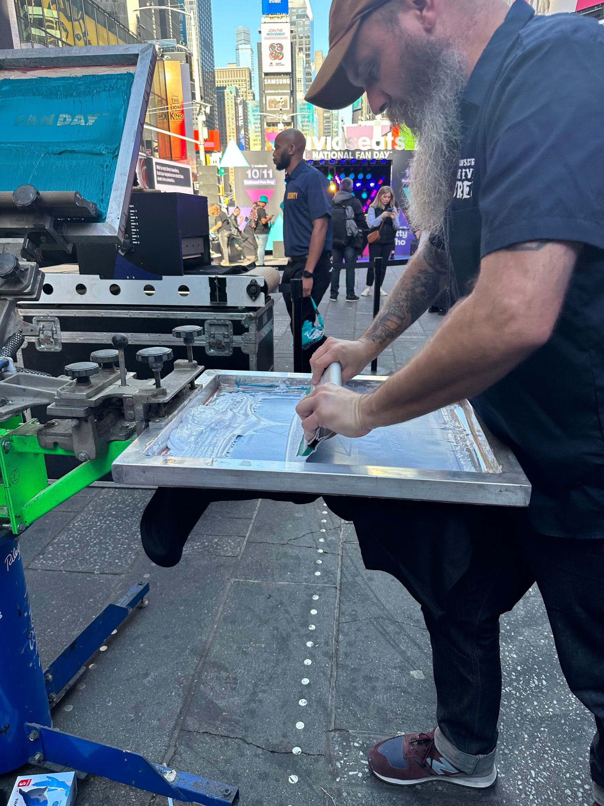 a man with a beard is working on a screen printing machine
