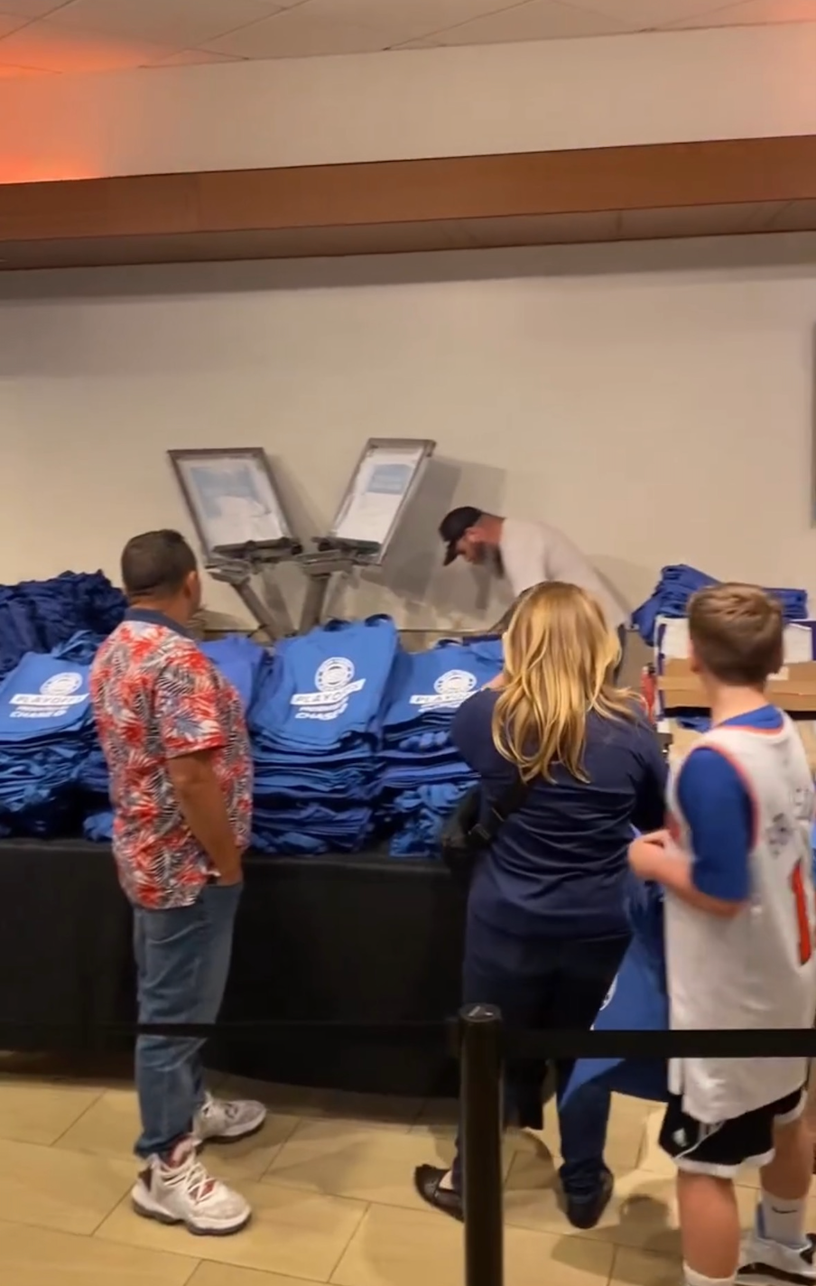 a group of people are standing in front of a table full of blue bags