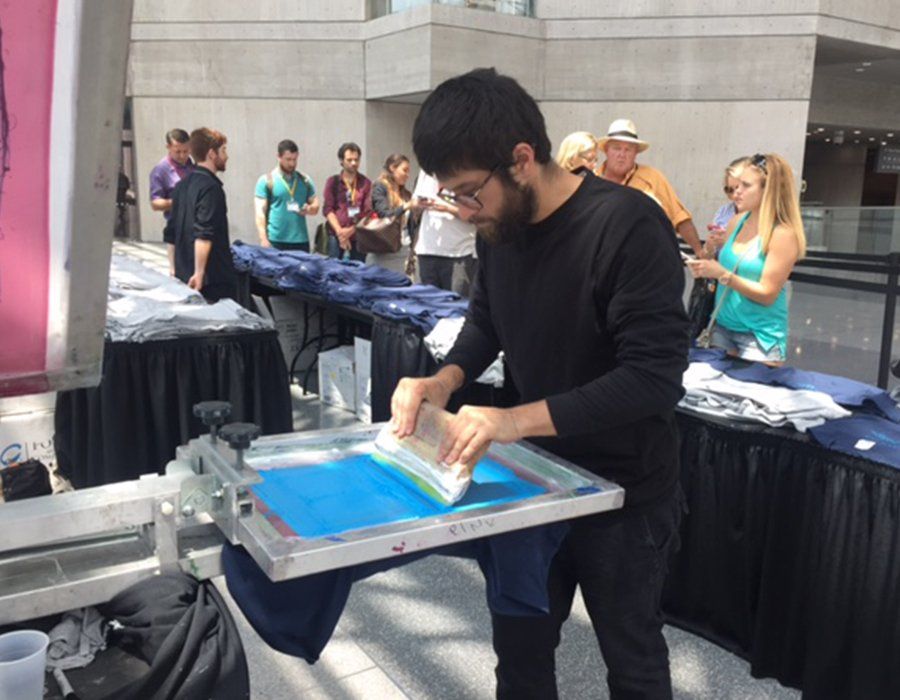 a man is using a screen printing machine to print a shirt