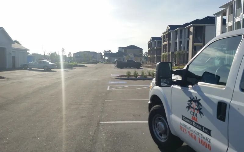 White service truck in a parking lot, with buildings in the background under a bright sky.