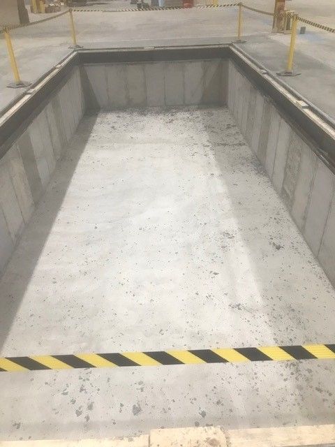 A large concrete pool with a yellow and black striped border