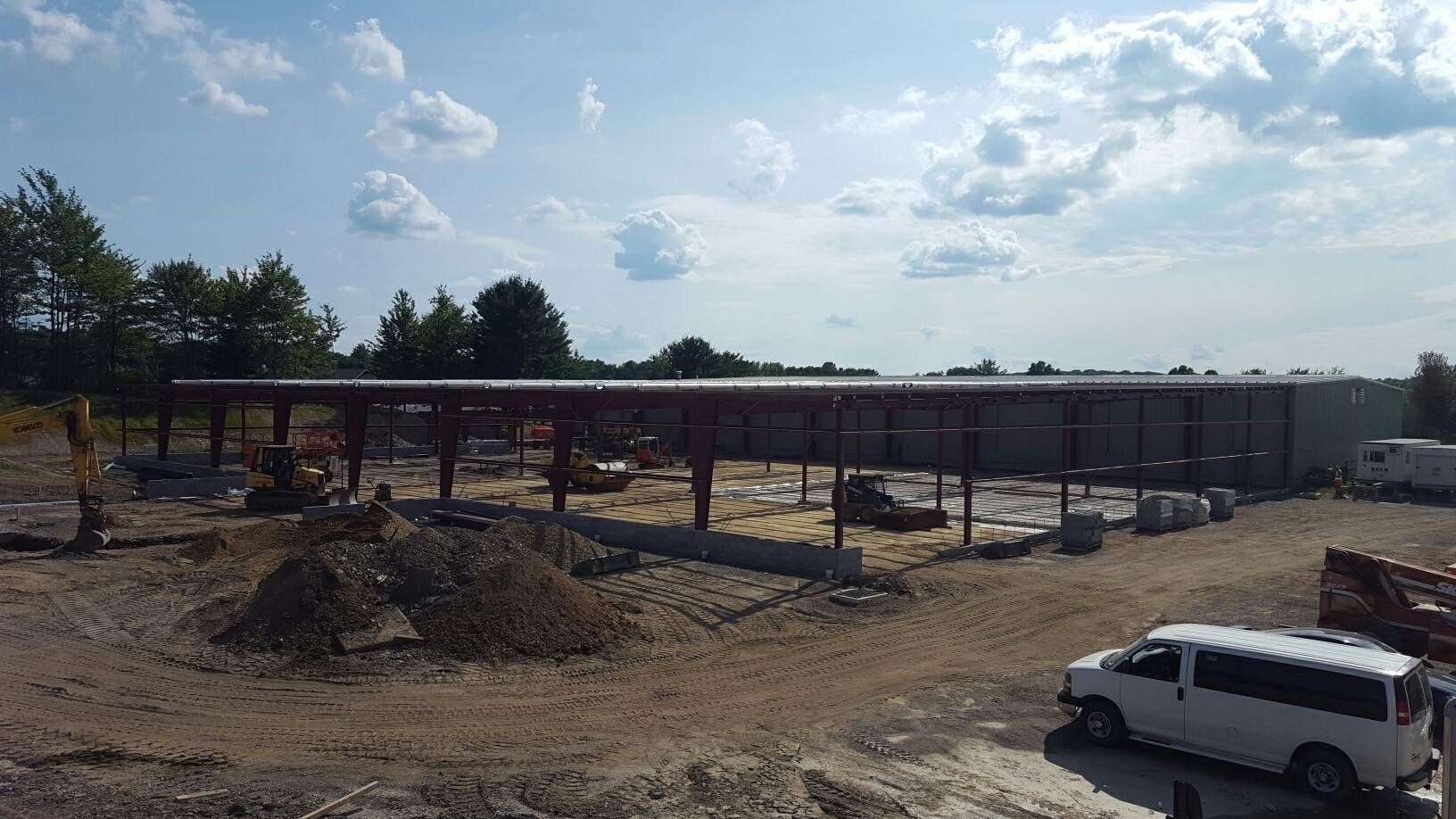 A white van is parked in front of a building under construction.