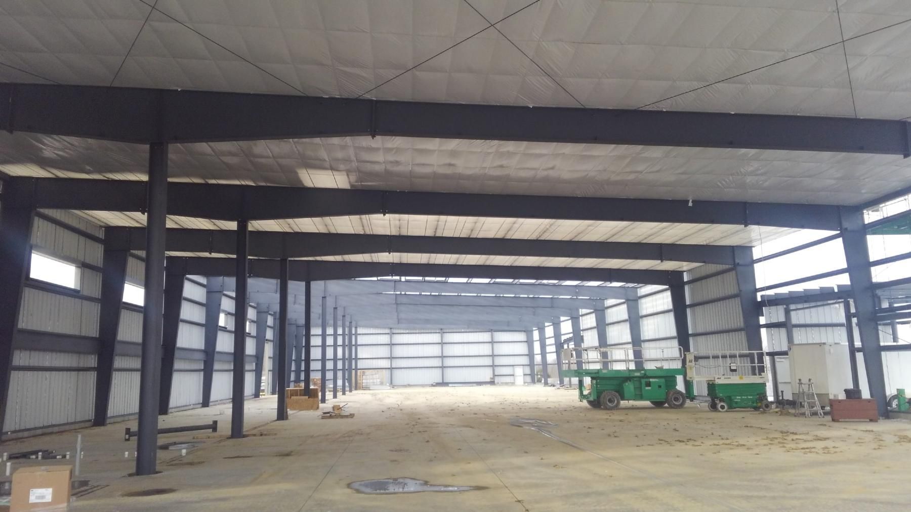 An empty warehouse with a green cart in the middle.