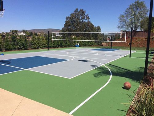 A basketball court with a volleyball net and a basketball hoop.